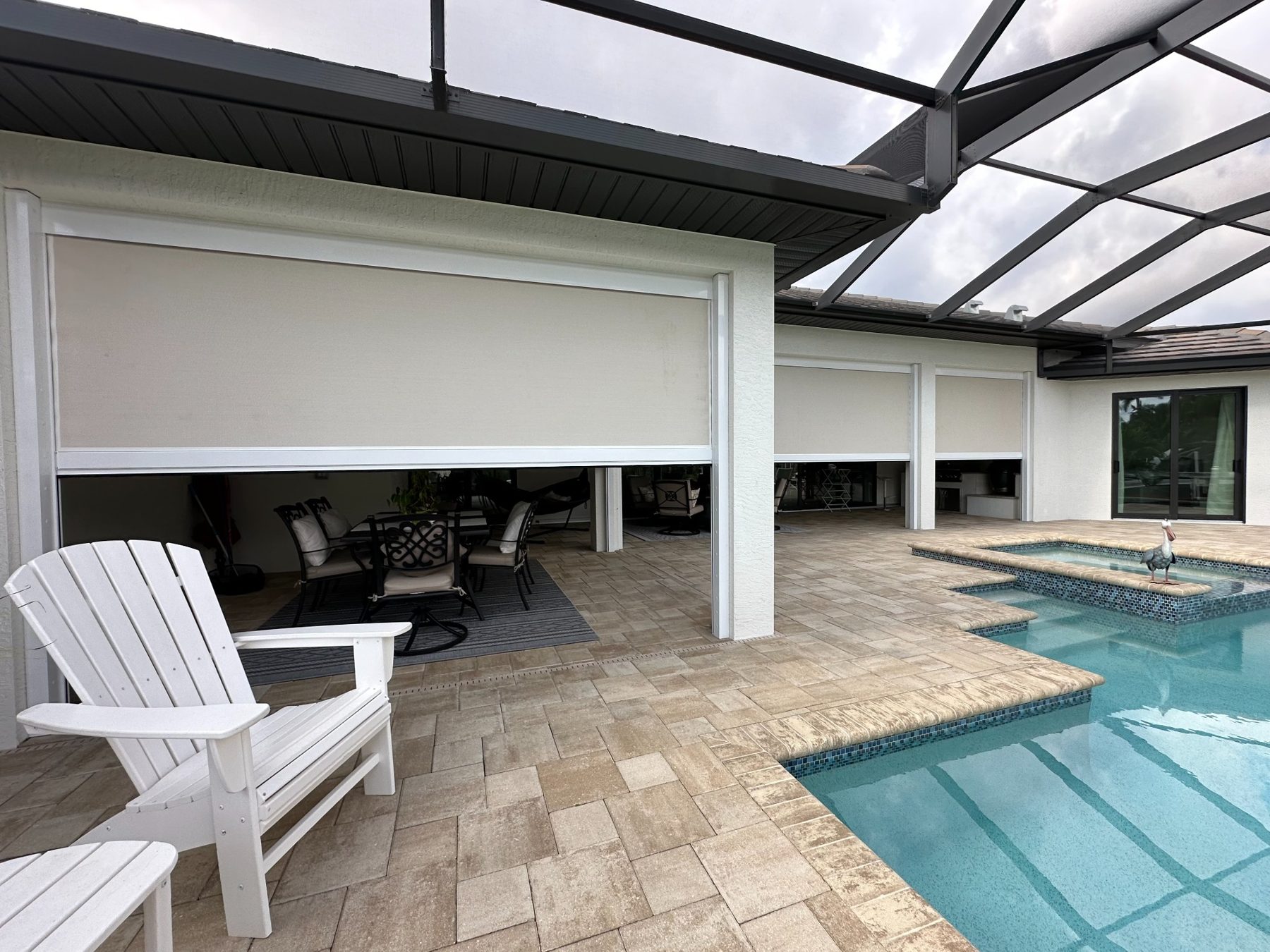Exterior view of a pool lanai with white-framed screens partly lowered